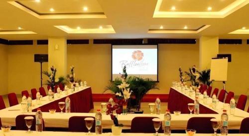 a meeting room with tables and chairs and a screen at Raffleshom Hotel in Bandung