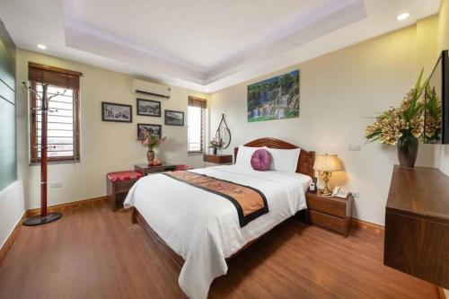 a bedroom with a large white bed and wooden floors at Viet Village Hotel in Hanoi