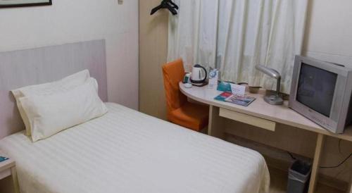 a hotel room with a bed and a desk with a television at Jinjiang Inn Select Shanghai International Tourism and Resorts Zone Chuansha Road Subway Station in Shanghai