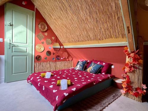 a bedroom with a bed with a red wall at Nature, évasion, jacuzzi, grande piscine et cinéma in Houdancourt
