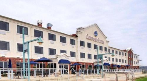 a large white building with blue umbrellas in front of it at Clarion Suites Vidalia Riverfront in Vidalia