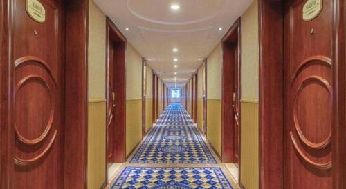 a long hallway with blue tile floors in a building at Yichang Vienna Hotel Wanda Branch in Yichang