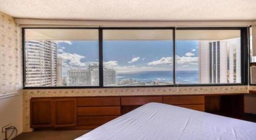 a bedroom with a large window with a view of a city at Marina Tower Waikiki in Honolulu