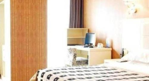 a bedroom with a bed and a desk with a computer at Chengdu Huadu Times Hotel in Chengdu