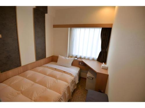 a bedroom with a bed and a desk and a window at Green Hill Hotel Urban in Kobe