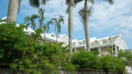 a white house with palm trees in front of it at Petit Hotel Key West Club in Naha