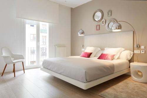 1 dormitorio blanco con 1 cama blanca grande con almohadas rojas en Zabaleta Beach by FeelFree Rentals, en San Sebastián