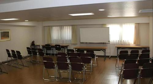 a lecture room with chairs and a white screen at Isehara Green Palace Hotel in Isehara