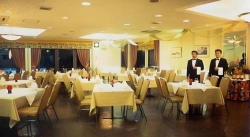 two men standing in front of a dining room with white tables at Okinawa Sunplaza Hotel in Naha
