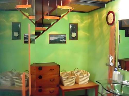 a room with a green wall with a staircase and baskets at Auberge Kitano Dandan in Abashiri