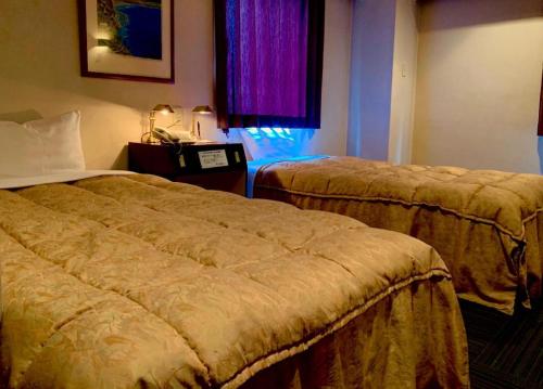a hotel room with two beds and a window at Shizuoka UI Hotel in Shizuoka