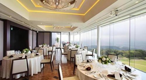 a restaurant with white tables and chairs and large windows at Nippondaira Hotel in Shizuoka
