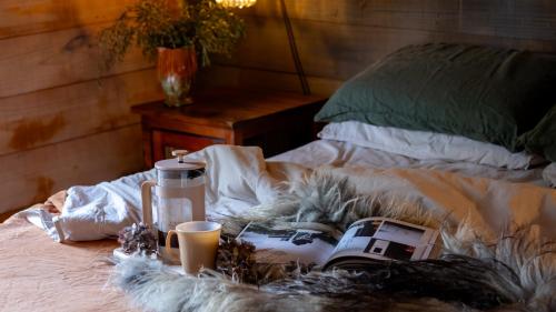 a bed with a camera and two cups on it at The Quarters in Strahan