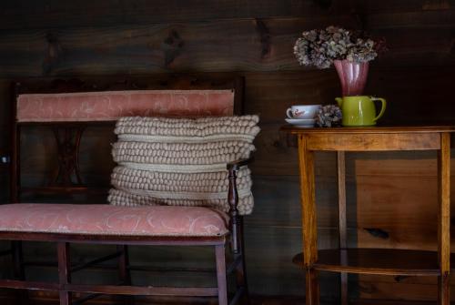 a chair and a table with a vase of flowers at The Quarters in Strahan