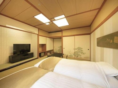a bedroom with a bed and a flat screen tv at Centurion Hotel Technoport Fukui- Artificial Radium Hot Spring in Sakai