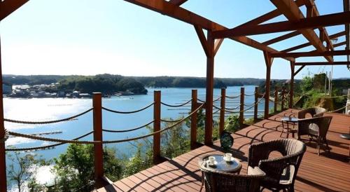 a deck with a table and chairs and a view of the water at Ikadasou Sanjou in Shima