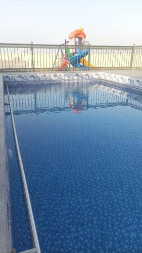 a swimming pool with a playground in the background at Ain almasfa house بيت عين المسفاة in Al Ḩamrāʼ