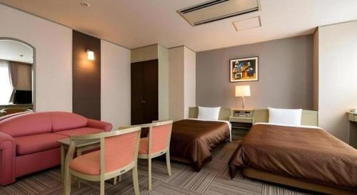 a hotel room with two beds and a pink couch at New Biwako Hotel in Otsu