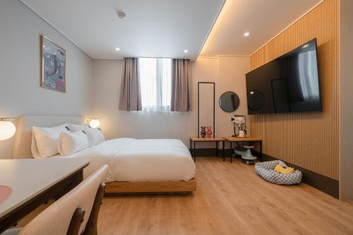 a hotel room with a bed and a flat screen tv at Browndot Gangneung Station in Gangneung