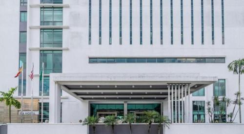 a white building with palm trees in front of it at RH Hotel Sibu in Sibu