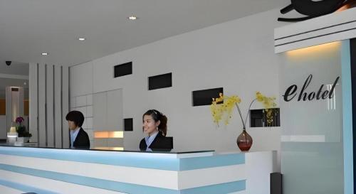 two women sitting at a counter in a lobby at e Hotel in Melaka