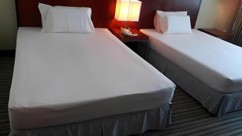 two beds in a hotel room with white sheets and pillows at RH Hotel Sibu in Sibu