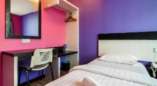 a bedroom with a bed and a desk and purple wall at e Hotel in Melaka