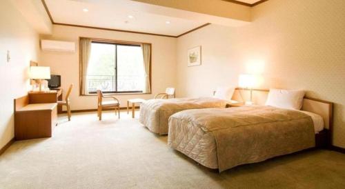 a hotel room with two beds and a desk and a window at HOTEL WINDSOR in Nakatsugawa