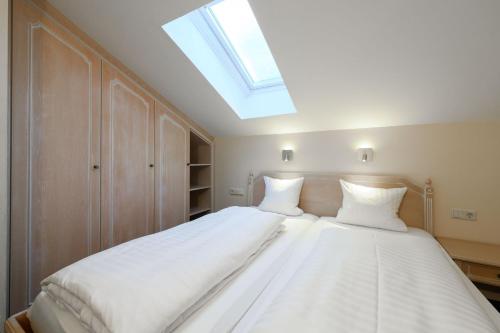 a bedroom with a large white bed with a skylight at Crystls Aparthotel in Flachau