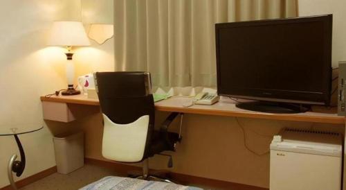 a desk with a computer monitor and a chair at Chino Station Hotel in Chino