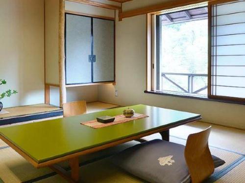 a dining room with a green table and two windows at Myoken Ishiharaso in Kirishima