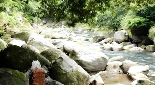 a river filled with rocks and trees and water at Myoken Ishiharaso in Kirishima