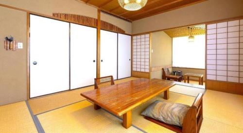 a room with a wooden table and some windows at Yukemuri no sato azumaya in Beppu