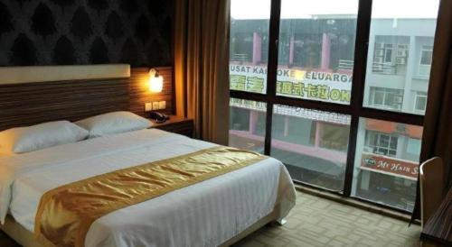 a bedroom with a large bed and a large window at Clover Hotel in Johor Bahru