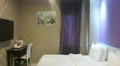 a hotel room with a bed and a desk and a window at Cappuccino Hotel @ Mount Austin in Johor Bahru