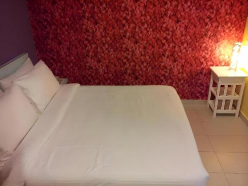a white bed in a room with a red wall at Cappuccino Hotel @ Mount Austin in Johor Bahru
