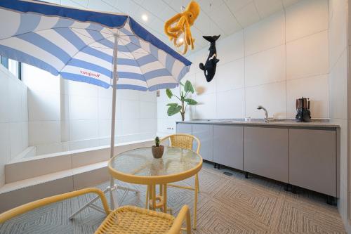 a table with a blue and white umbrella in a kitchen at Browndot Gangneung Station in Gangneung