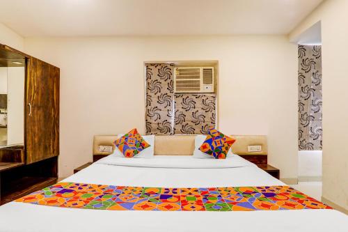 a bedroom with a large white bed with colorful pillows at FabExpress Travellers in Lucknow