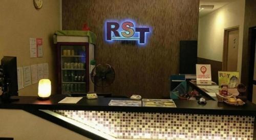a reception desk with a rs t sign on the wall at RST Hotel in Johor Bahru