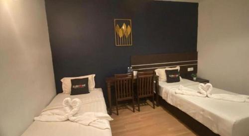 two beds in a room with white sheets at Alia Express Sendayan in Seremban