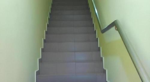 a staircase in a building with white floors and green railing at RST Hotel in Johor Bahru