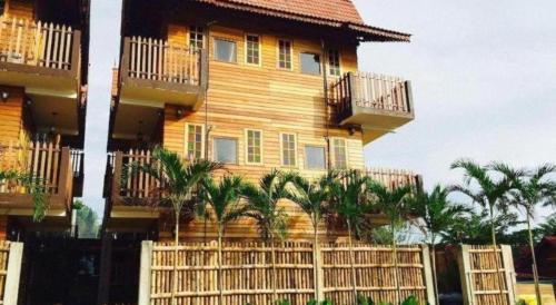 a building with palm trees in front of a fence at Kampong Pinang Sebatang Melaka in Melaka
