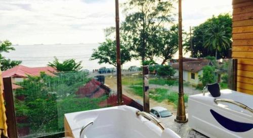 a bathroom with a tub and a window with a view of the ocean at Kampong Pinang Sebatang Melaka in Melaka