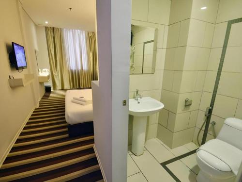 a bathroom with a toilet and a sink and a bed at First Residence Hotel Kemaman in Cukai