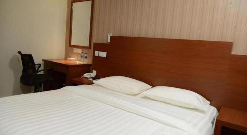 a bedroom with a large bed with a wooden headboard at Elegant Hotel in Batu Pahat