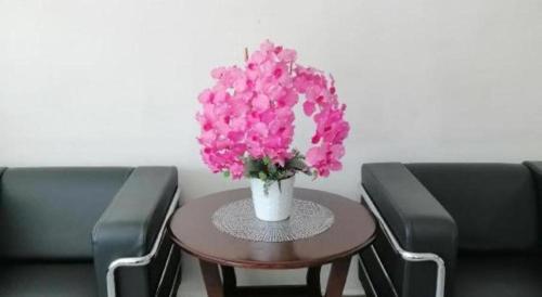 a vase with pink flowers on a table between two chairs at Hotel Darulaman Alor Setar in Alor Setar