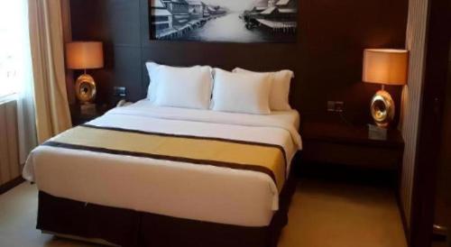 a large bed in a hotel room with two lamps at MB Hotel in Tawau