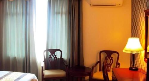 a bedroom with two chairs and a table and a bed at MB Hotel in Tawau