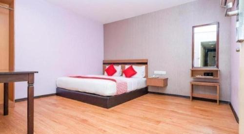 a bedroom with a bed with red pillows and a desk at Hotel Aromas Kulai in Johor Bahru