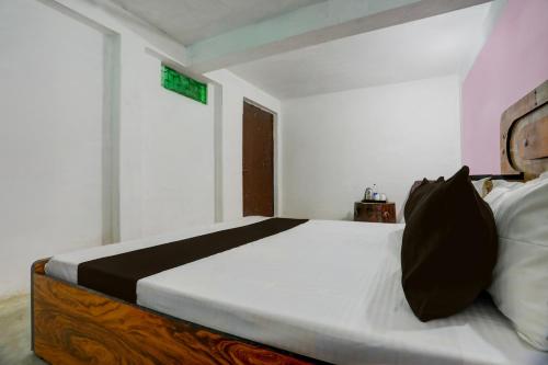 a bedroom with a bed with white sheets and black pillows at SPOT ON Hotel Sukun in Handiā
